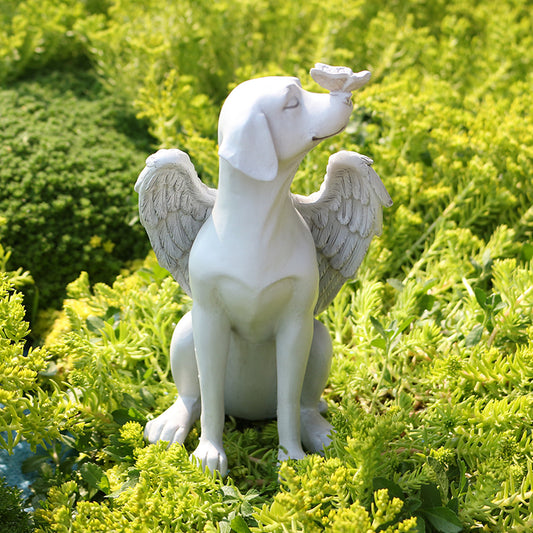 Front view of winged angel dog memorial statue in a garden