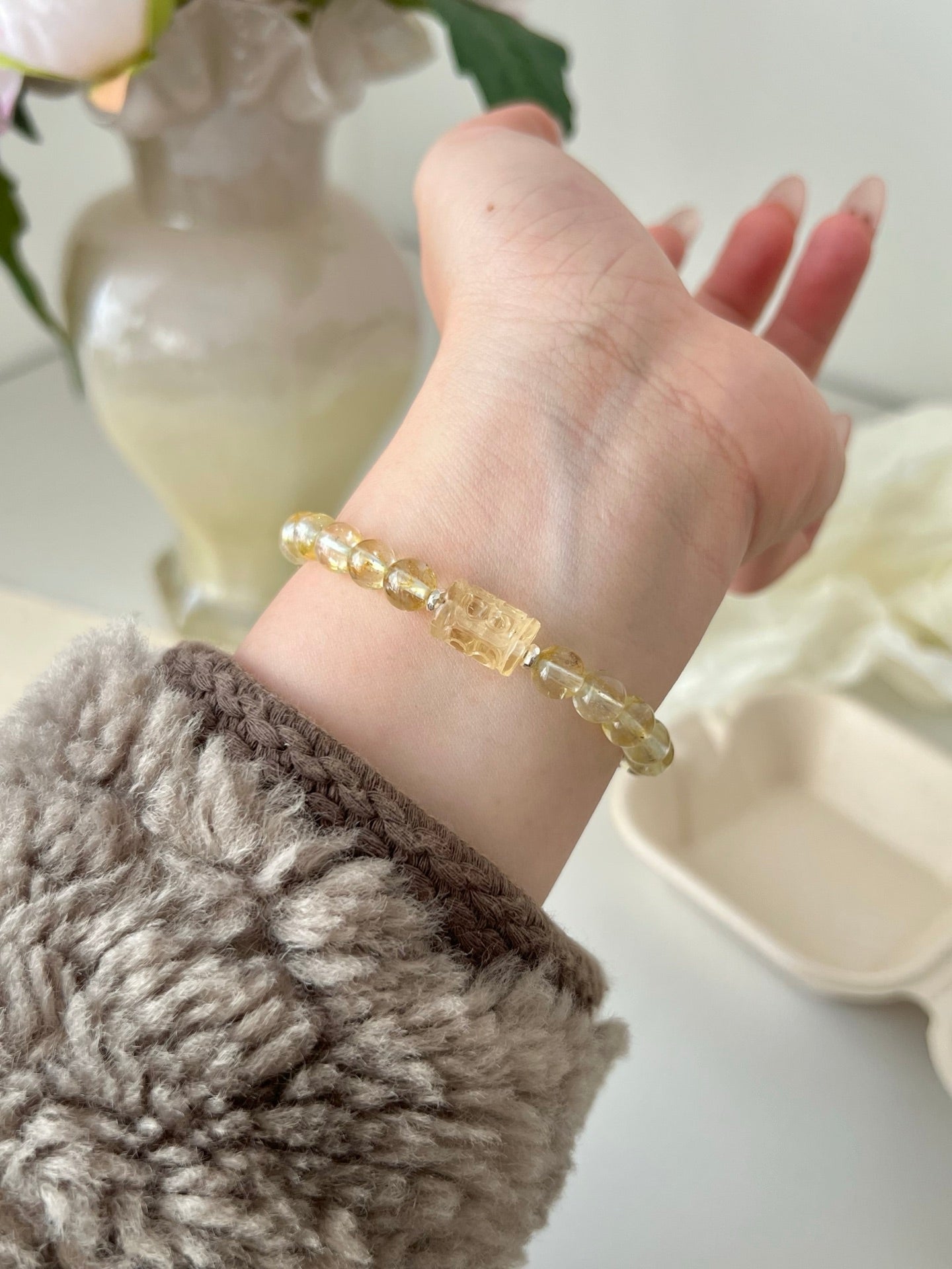 Yellow patterned barrel bead bracelet worn on wrist